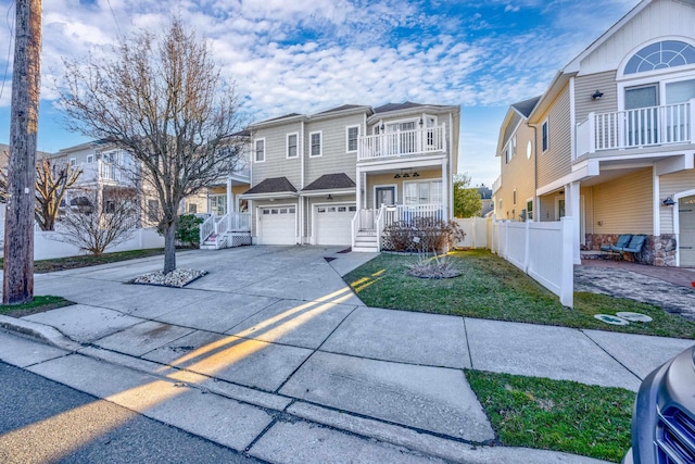 view of front of property with a balcony, a garage, fence, driveway, and a front lawn