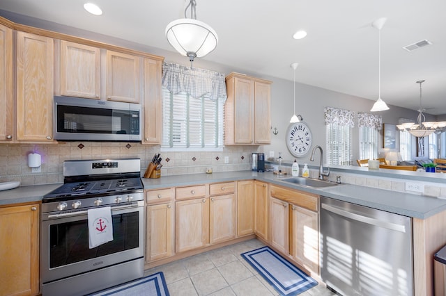 kitchen featuring visible vents, a peninsula, stainless steel appliances, light brown cabinets, and a sink