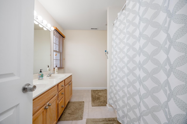 bathroom featuring tile patterned flooring, a sink, visible vents, baseboards, and double vanity