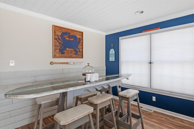 dining space with hardwood / wood-style flooring, ornamental molding, bar area, and wooden ceiling