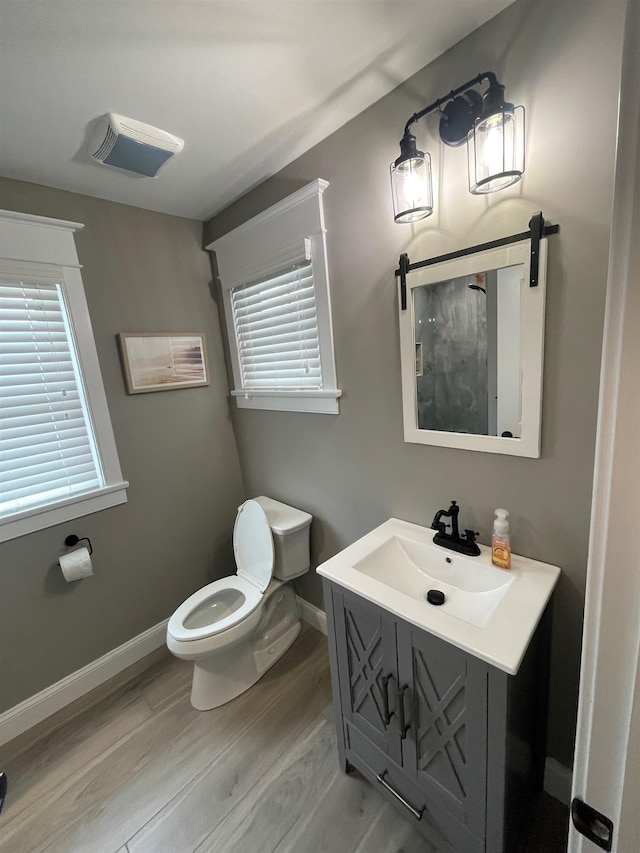 bathroom featuring toilet, vanity, a healthy amount of sunlight, and hardwood / wood-style flooring