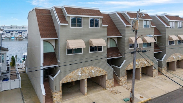 view of front of property with a water view, stone siding, and roof with shingles