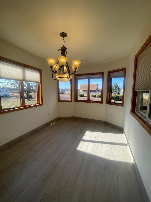 unfurnished room with a chandelier and hardwood / wood-style flooring