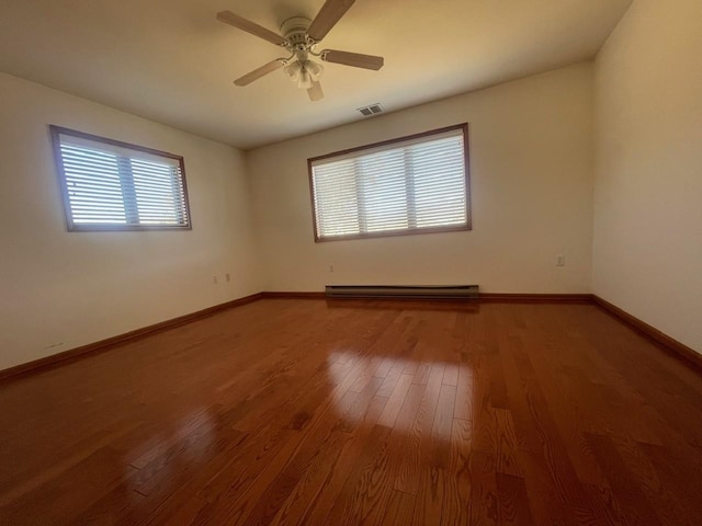 unfurnished room with wood-type flooring, baseboard heating, a wealth of natural light, and ceiling fan