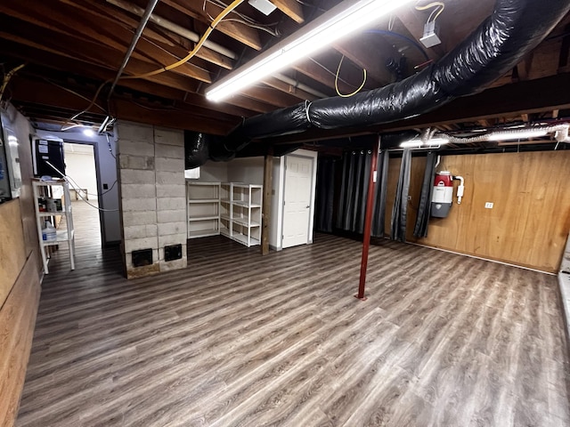 basement featuring hardwood / wood-style floors and water heater