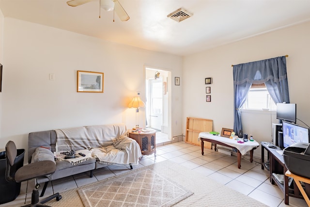 living area with tile patterned flooring, visible vents, and a ceiling fan