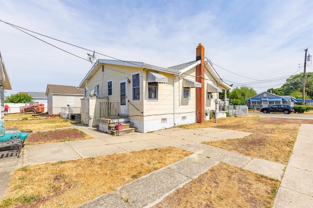 view of front of property featuring crawl space, a chimney, and fence