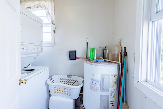 clothes washing area with laundry area, stacked washing maching and dryer, and electric water heater