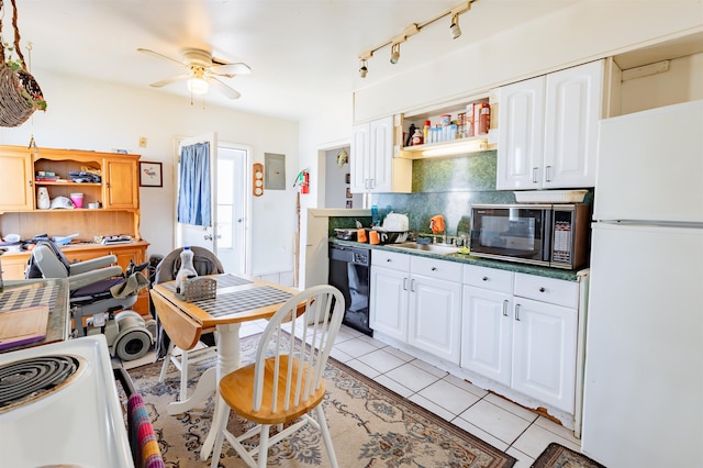 kitchen featuring light tile patterned flooring, a sink, white cabinets, backsplash, and black appliances