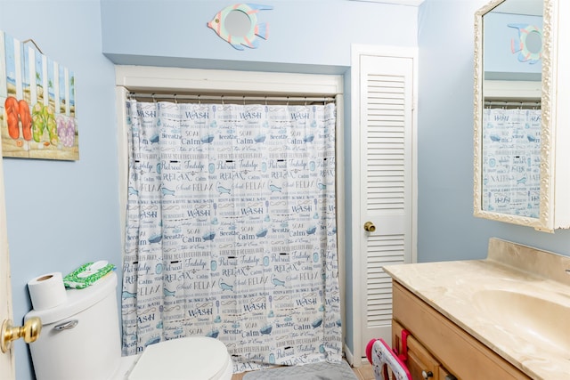 full bath featuring toilet, a shower with shower curtain, a closet, and vanity