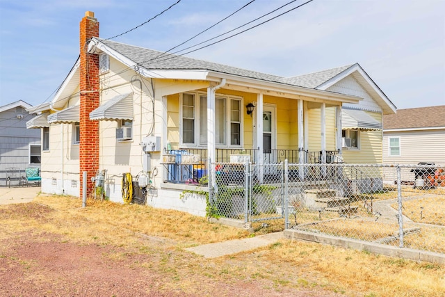 bungalow-style house featuring covered porch, a chimney, fence, and roof with shingles