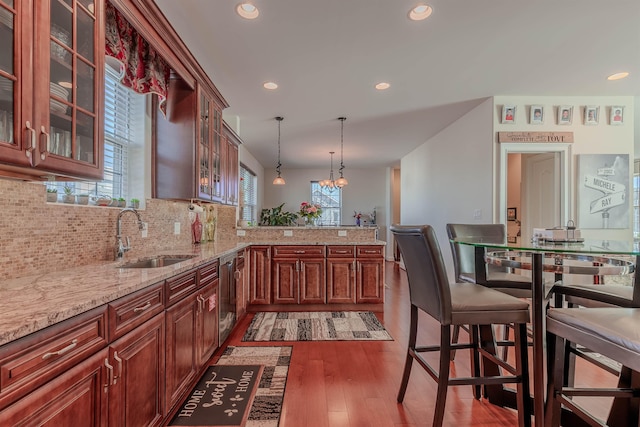 kitchen featuring dishwasher, a sink, glass insert cabinets, and decorative light fixtures