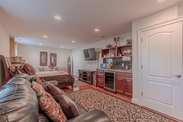 living area featuring beverage cooler, visible vents, a bar, light wood-style floors, and recessed lighting