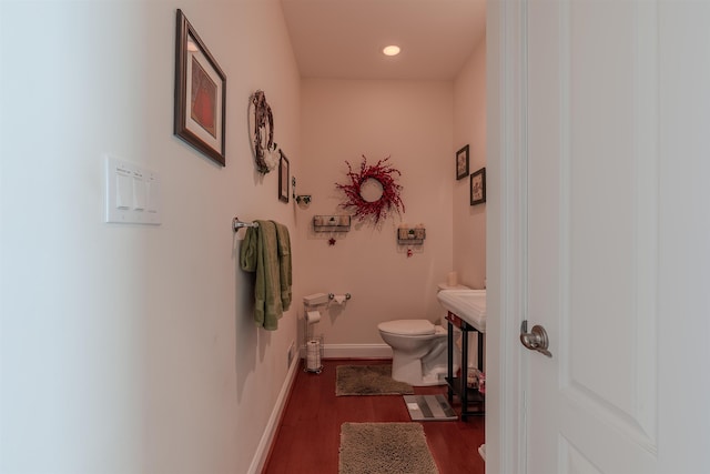 bathroom featuring toilet, baseboards, wood finished floors, and recessed lighting