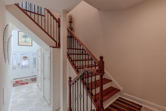 stairs with a high ceiling, visible vents, and baseboards