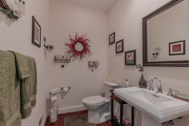 bathroom with visible vents, toilet, a sink, wood finished floors, and baseboards