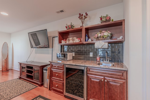 bar featuring visible vents, decorative backsplash, a sink, wet bar, and beverage cooler