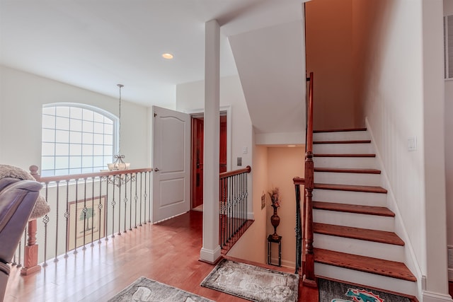 stairs with wood finished floors and recessed lighting