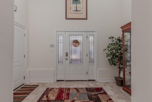 entryway with baseboards and a high ceiling