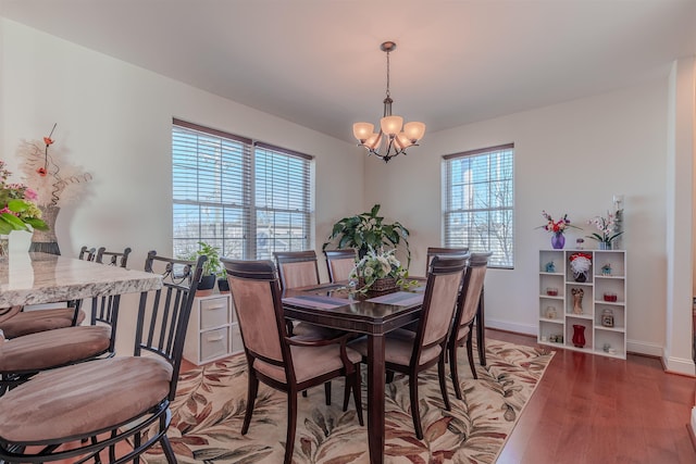 dining room with an inviting chandelier, baseboards, and wood finished floors