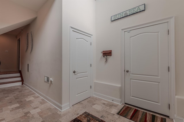 entrance foyer featuring stone finish flooring, stairs, and baseboards