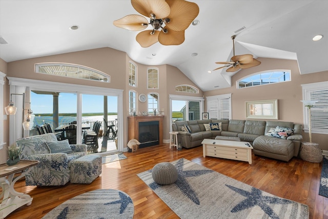 living room featuring a healthy amount of sunlight, a water view, light wood-type flooring, and high vaulted ceiling