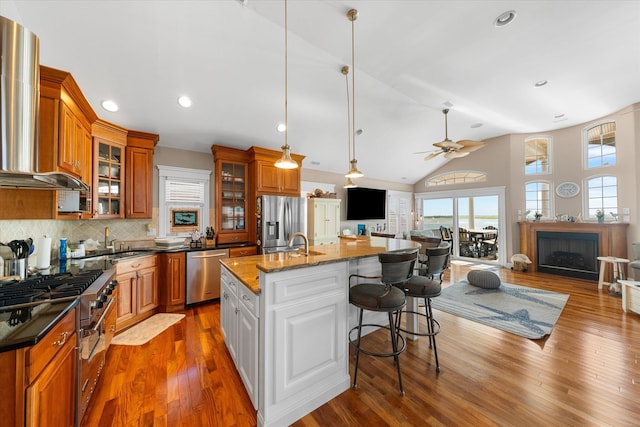 kitchen featuring white cabinetry, dark stone counters, a kitchen island with sink, a breakfast bar, and appliances with stainless steel finishes