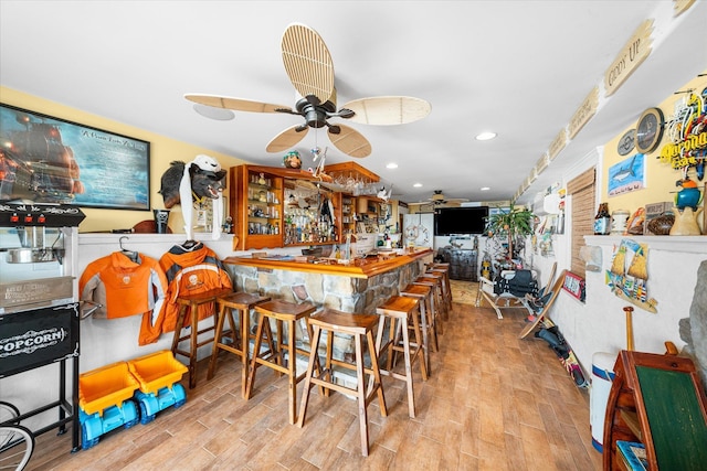 interior space with kitchen peninsula, a kitchen bar, light hardwood / wood-style flooring, and ceiling fan