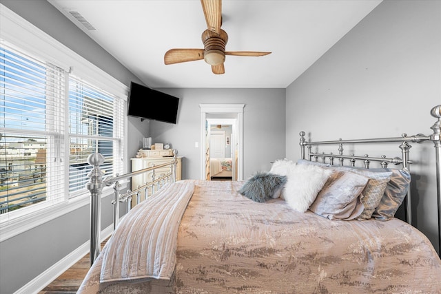 bedroom with hardwood / wood-style flooring, ceiling fan, and multiple windows