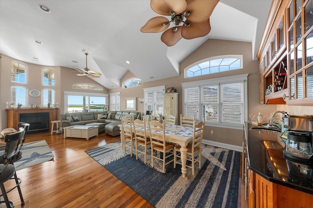 dining space with hardwood / wood-style floors, ceiling fan, a healthy amount of sunlight, and high vaulted ceiling