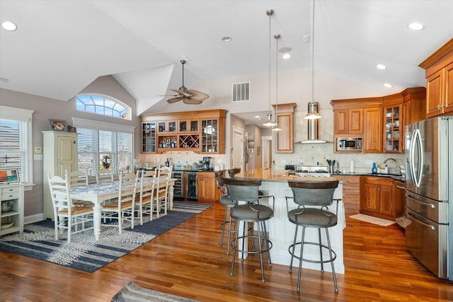 kitchen with backsplash, stainless steel appliances, pendant lighting, a center island, and lofted ceiling