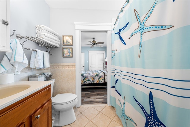 bathroom with vanity, ceiling fan, tile walls, tile patterned flooring, and toilet