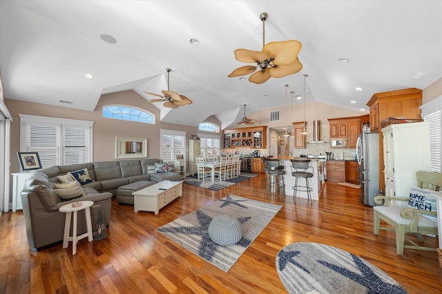 living room with ceiling fan, lofted ceiling, and light hardwood / wood-style flooring