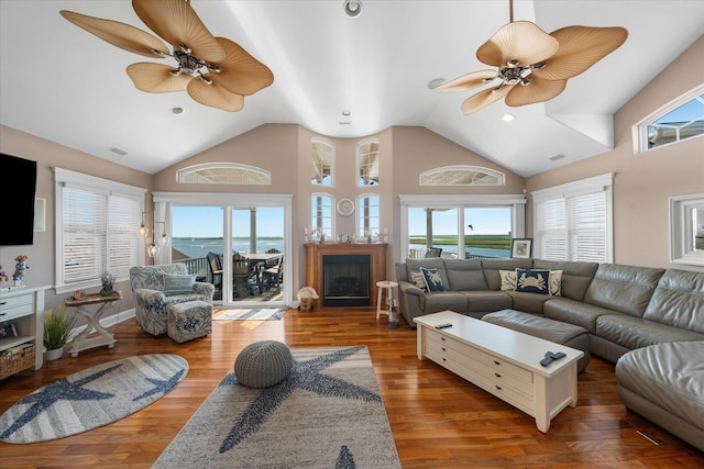 living room with a towering ceiling, a water view, and hardwood / wood-style flooring