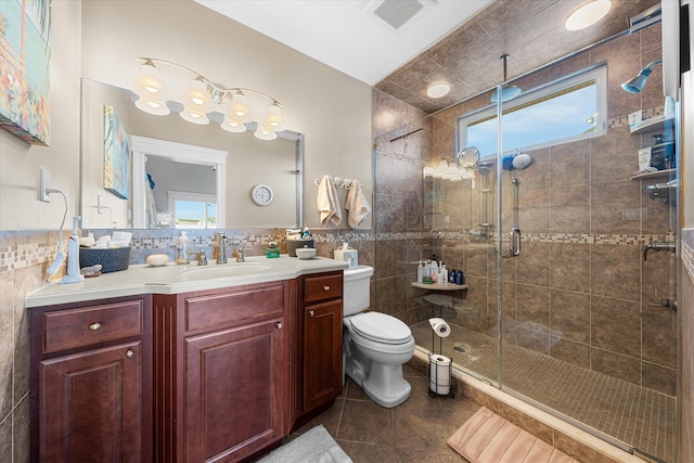 bathroom with a wealth of natural light, vanity, toilet, and tile walls