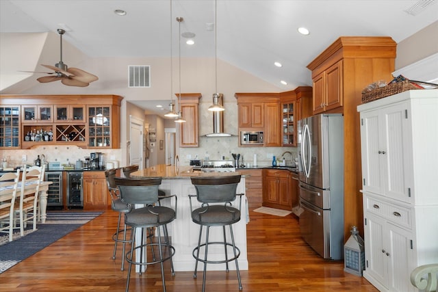 kitchen with a center island, a kitchen breakfast bar, decorative backsplash, appliances with stainless steel finishes, and decorative light fixtures