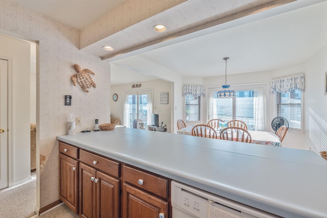 kitchen featuring light countertops, plenty of natural light, brown cabinetry, and decorative light fixtures