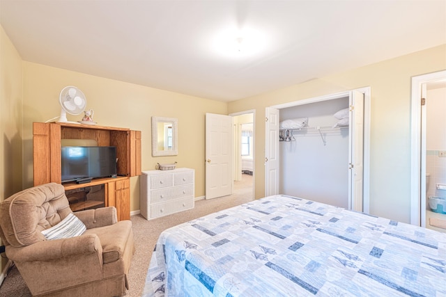bedroom featuring baseboards, a closet, ensuite bath, and light colored carpet