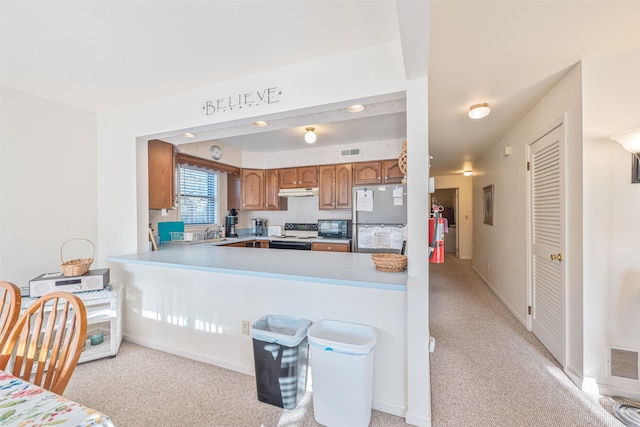 kitchen with black microwave, brown cabinetry, freestanding refrigerator, visible vents, and range with electric stovetop