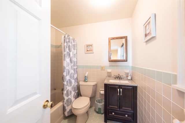 bathroom featuring vanity, toilet, shower / bath combination with curtain, a wainscoted wall, and tile walls
