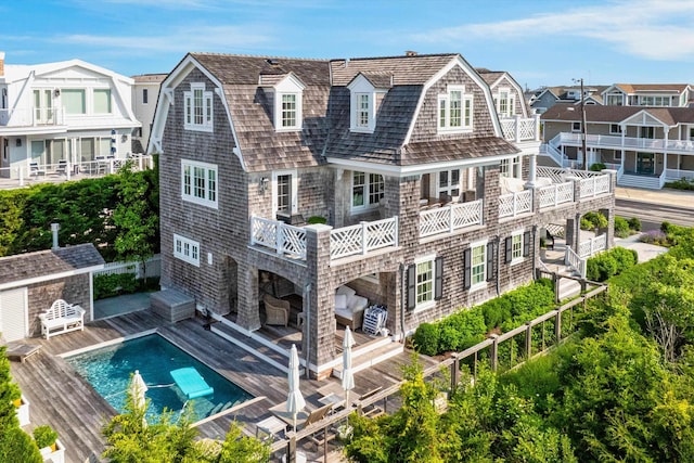 74 38th St, Avalon, NJ 08202 - back of property with an outdoor pool, a deck, a gambrel roof, and an outbuilding