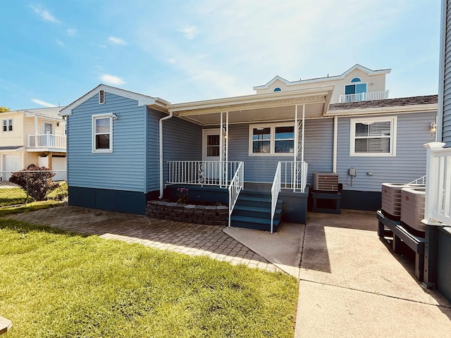 back of house with a porch, a lawn, central air condition unit, and fence