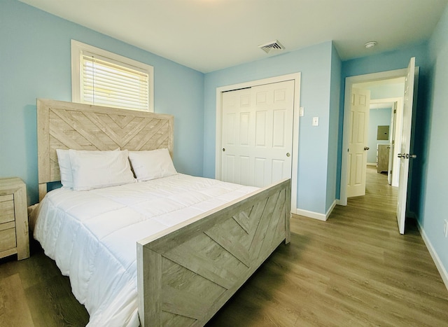bedroom featuring baseboards, wood finished floors, and visible vents