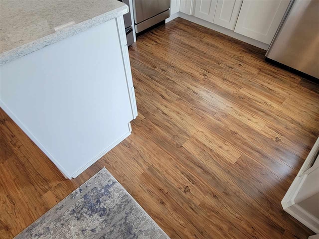 details with white cabinets, light hardwood / wood-style floors, and light stone counters