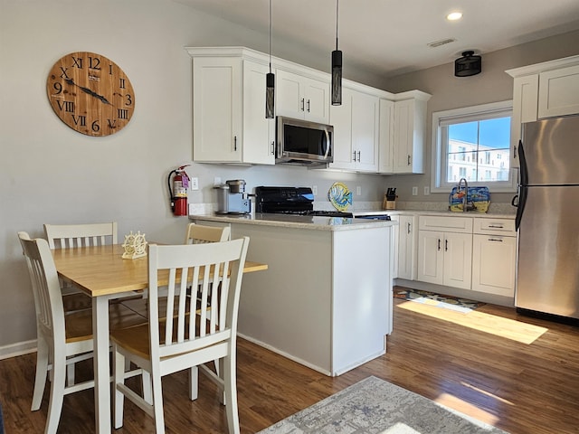 kitchen with a center island, white cabinets, dark hardwood / wood-style floors, decorative light fixtures, and stainless steel appliances