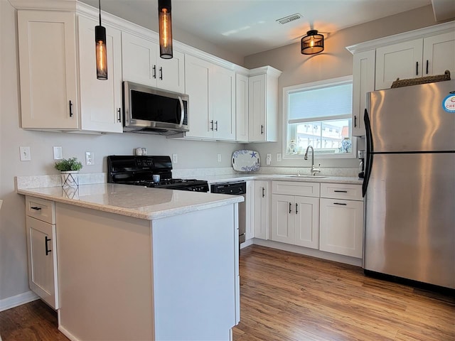 kitchen featuring sink, hanging light fixtures, light wood-type flooring, white cabinetry, and stainless steel appliances