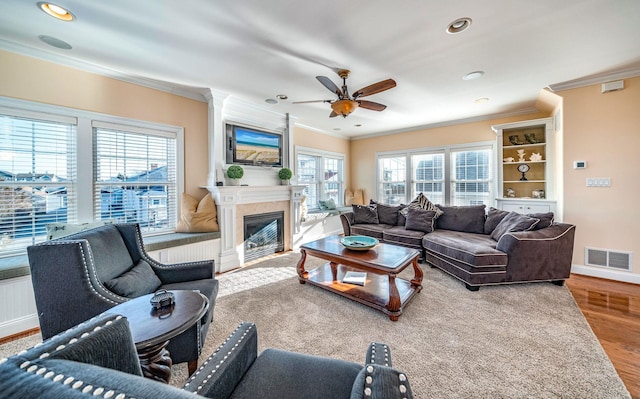 living room featuring ornamental molding, a large fireplace, hardwood / wood-style floors, and ceiling fan