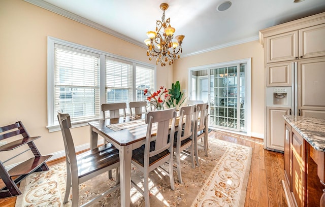 dining space with crown molding, light hardwood / wood-style floors, and an inviting chandelier