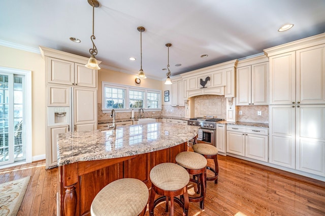 kitchen with light stone countertops, a kitchen island, pendant lighting, and stainless steel stove