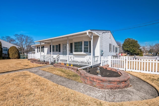 ranch-style home featuring a front yard, covered porch, and fence